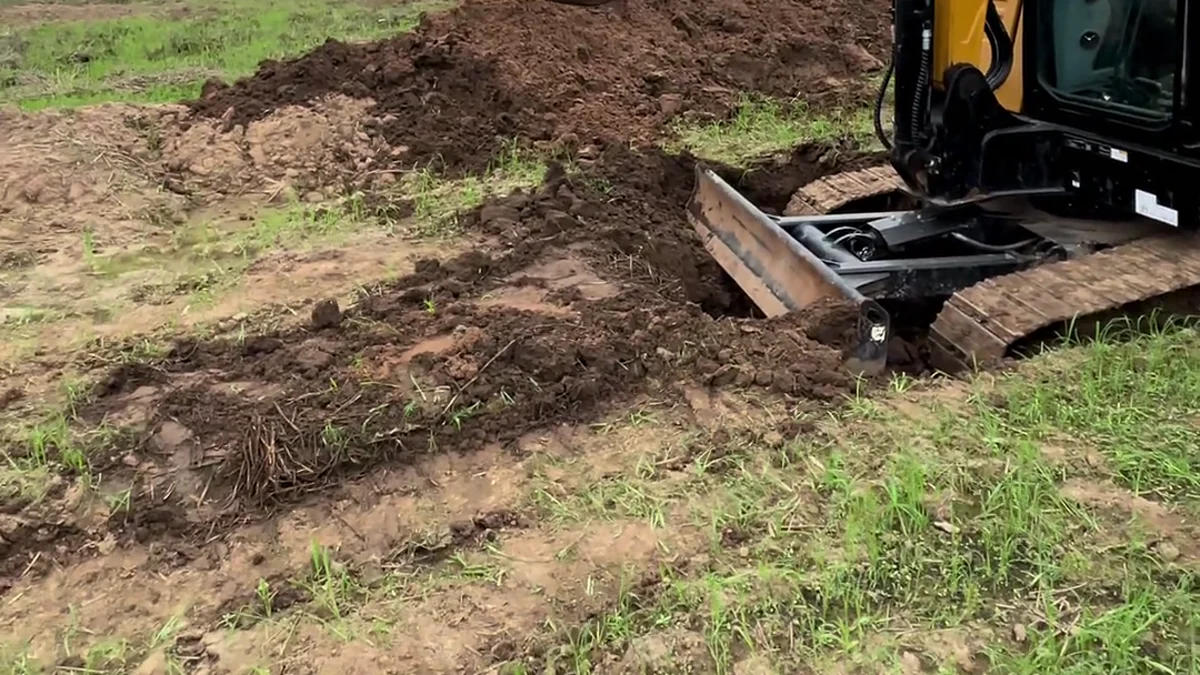 Excavator bucket and blade arranged near muddy ground